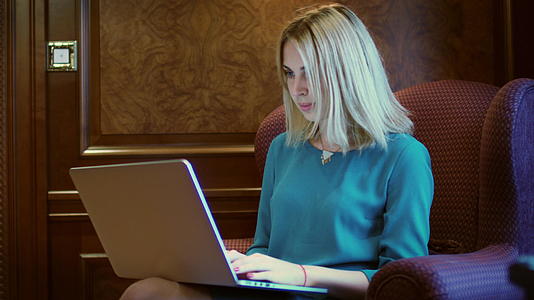 坐在家庭办公桌上的笔记本屏幕上的漂亮女士视频的预览图