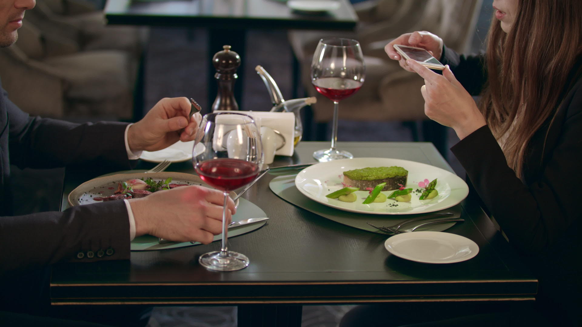 一位女士在餐厅用智能手机拍摄食物视频的预览图