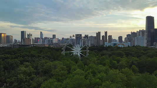 航拍城市风光夕阳晚霞天空落日余晖下的森林公园摩天轮城市风景素材视频的预览图