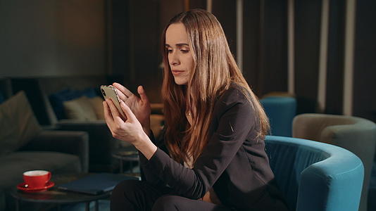 愤怒的女商人通过手机在酒店休息室进行视频通话视频的预览图