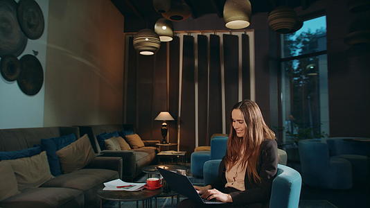 在酒店大厅做笔记本电脑工作的快乐女人视频的预览图
