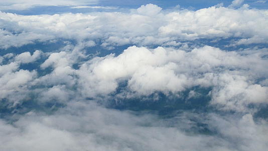 通过飞机窗口的鸟瞰图美丽的白云在蓝天的背景下飞行视频的预览图