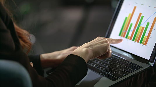 手指笔记本电脑屏幕上的商业女性图表视频的预览图