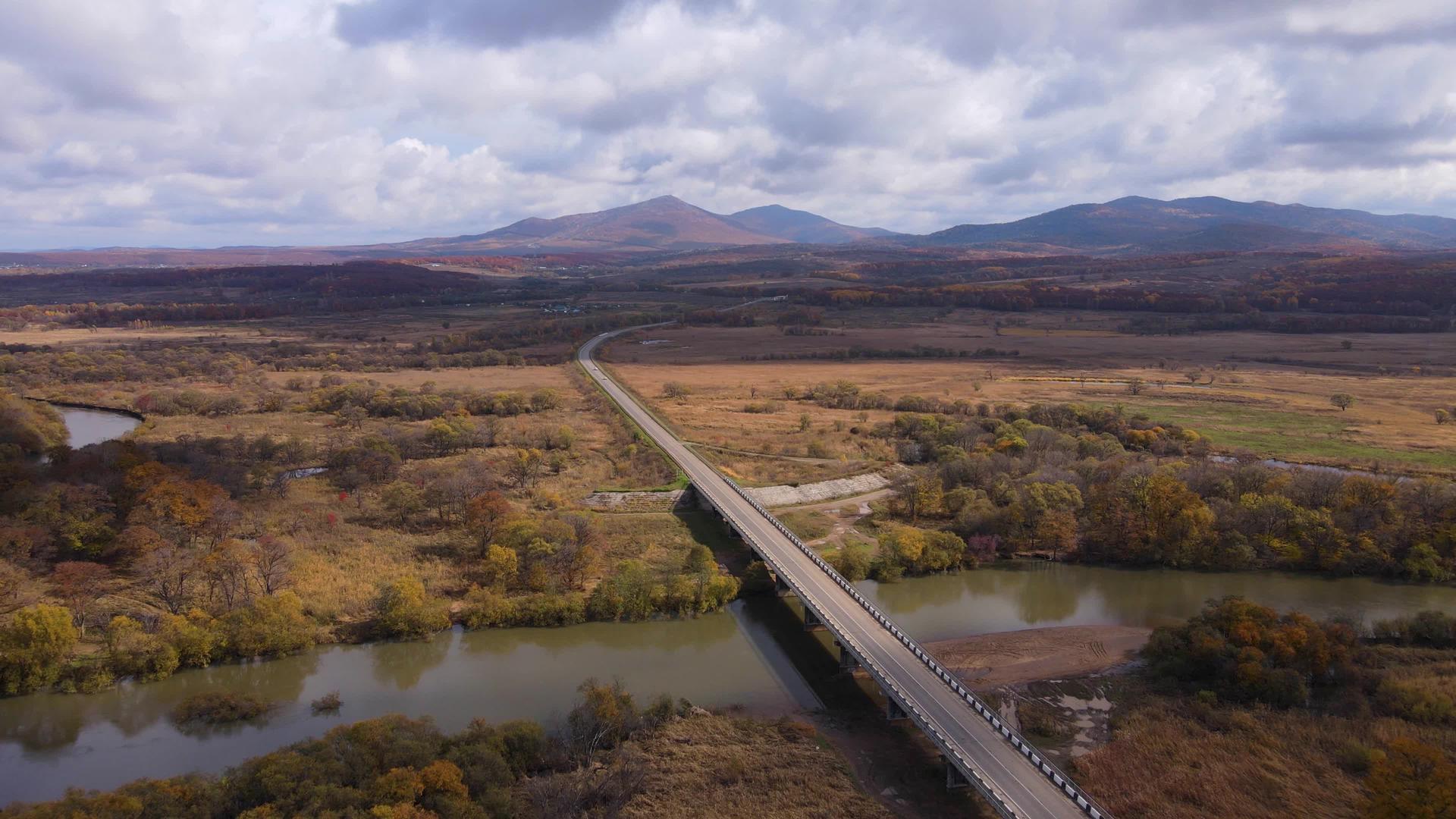 摄像机飞过一条小河上的公路桥平原景观视频的预览图