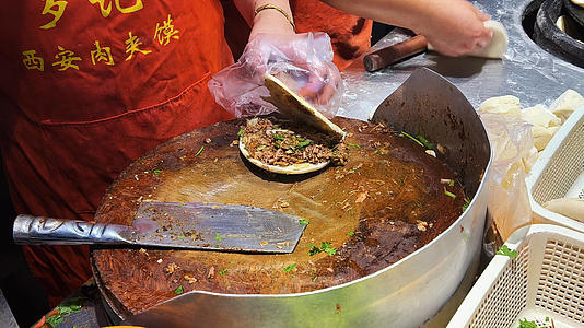 西安城市地方特色美食街头小吃肉夹馍制作过程4k素材视频的预览图