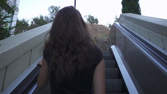 女人在扶梯上慢慢移动的美丽女孩爬上扶梯视频的预览图