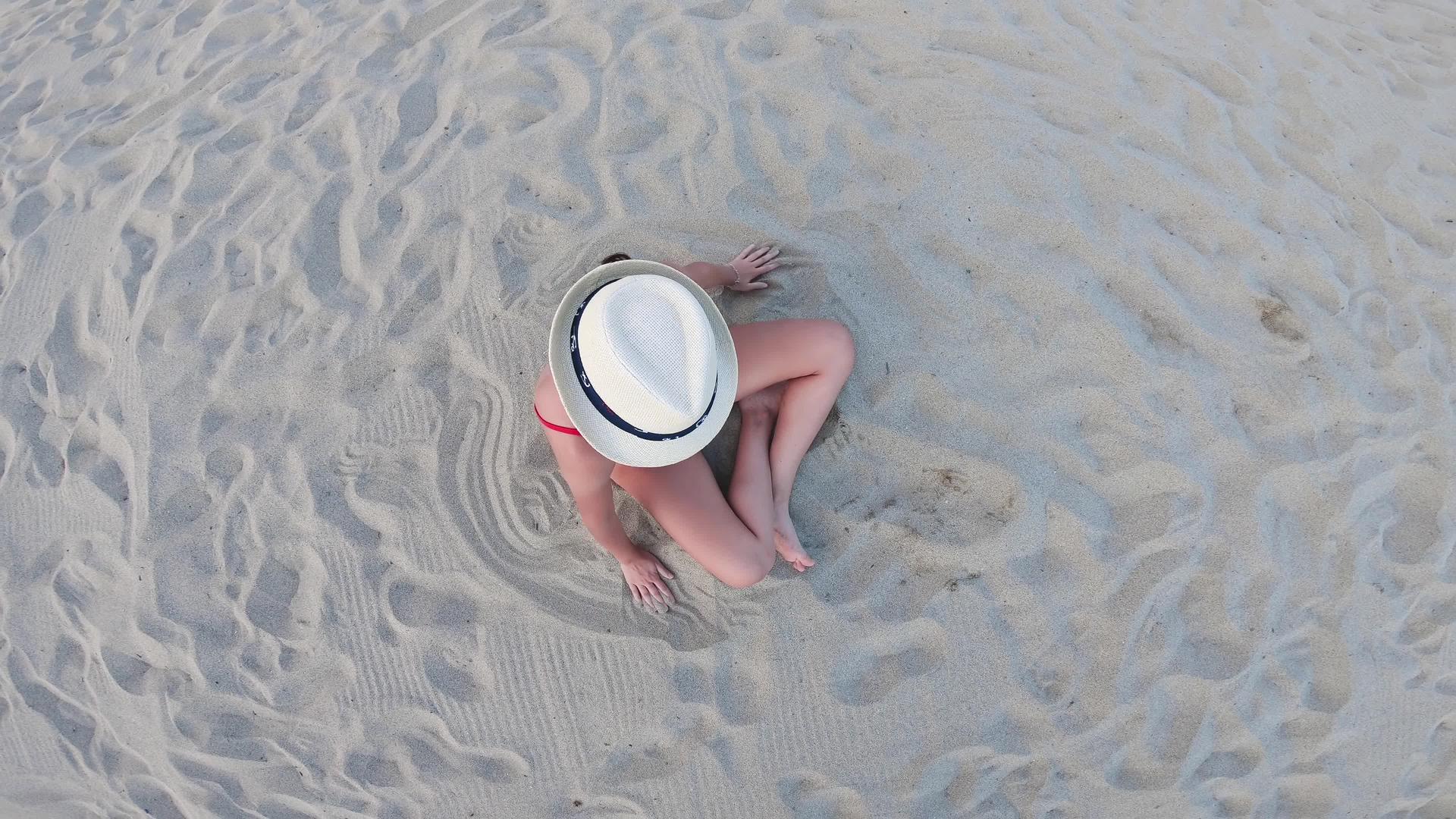 戴着白帽子的年轻女子坐在沙滩上在空中休息视频的预览图