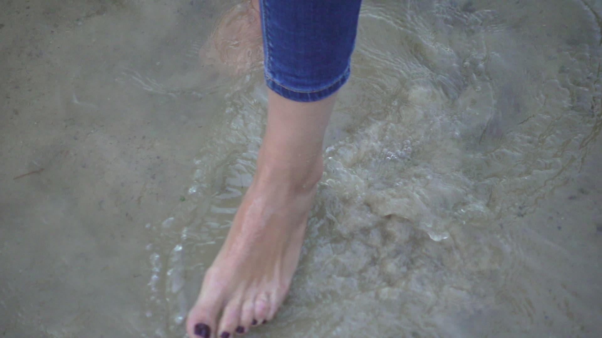 底沙移动海水的女性赤脚站立视频的预览图