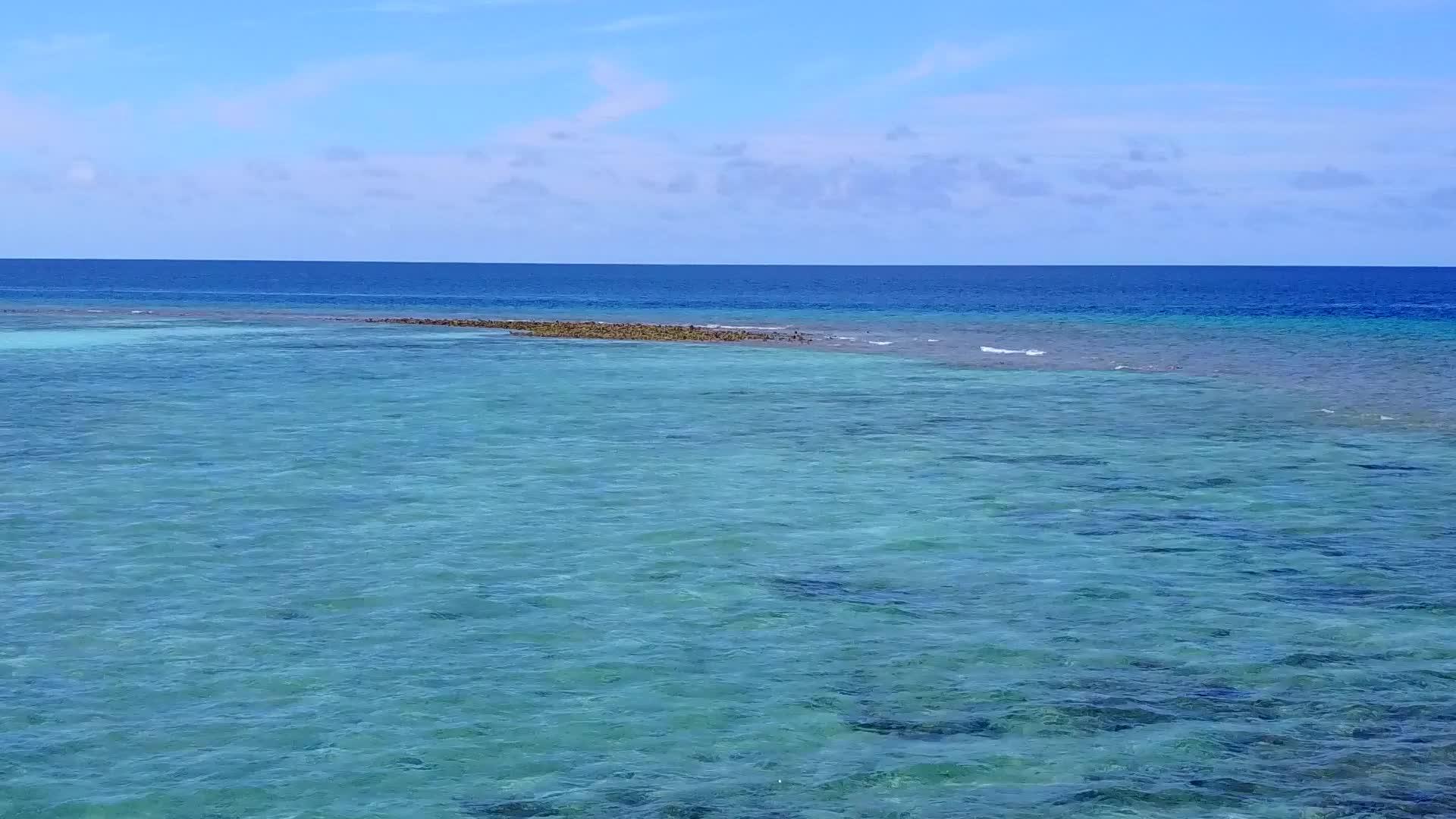以蓝环礁湖和白沙为背景的无人飞机在海滩上间歇性飞行视频的预览图