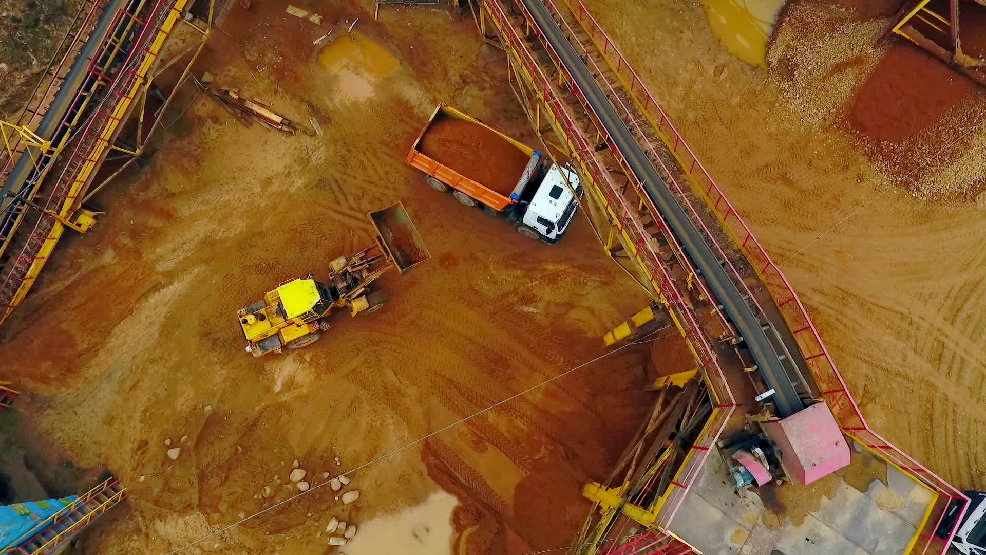 在空中观察沙堆工作用于倾倒卡车装载砂的挖掘机视频的预览图
