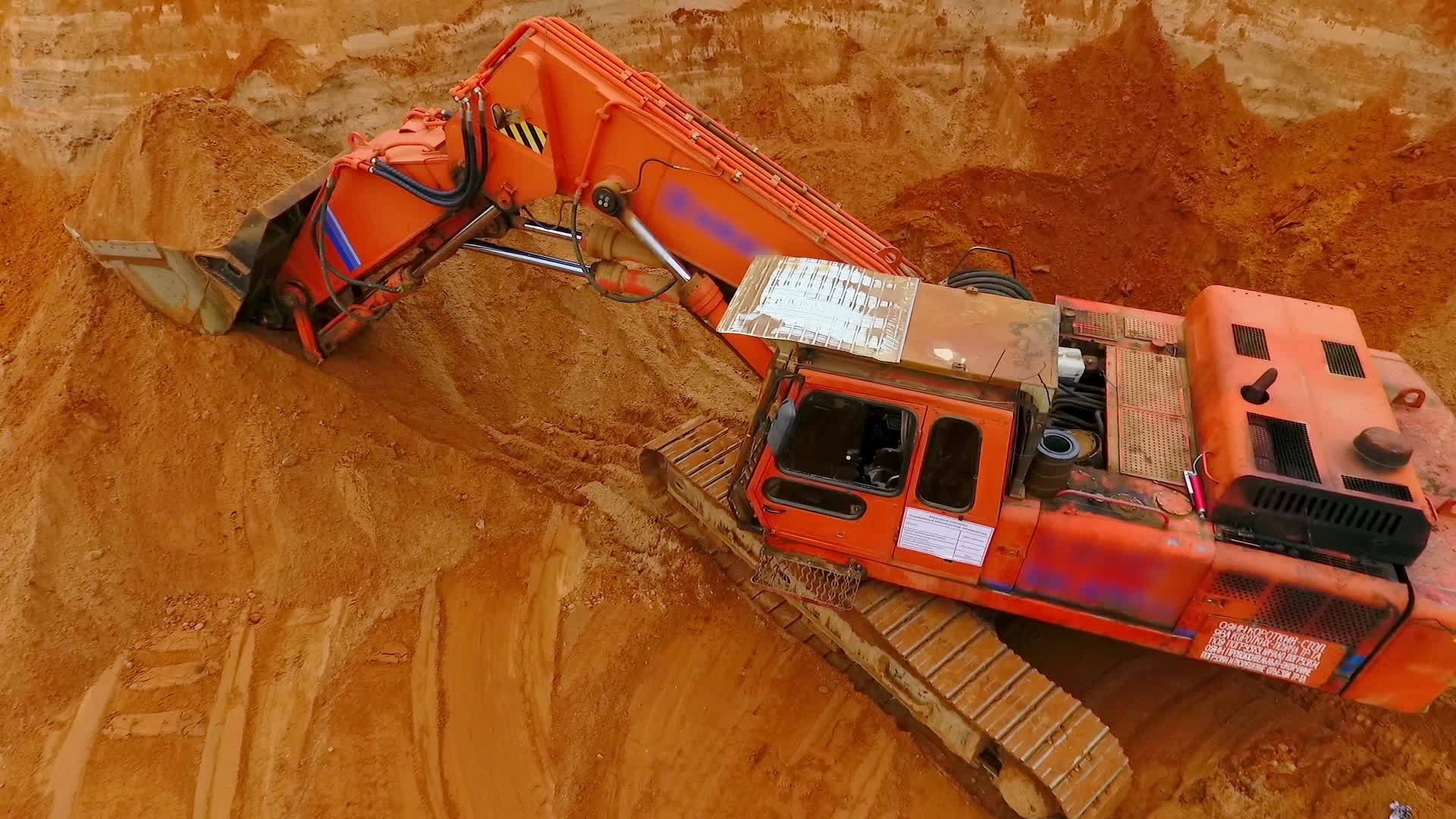 站在沙矿上的橙色爬行挖掘机视频的预览图