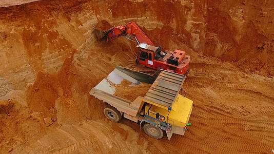 在采石场的采矿卡车上倒砂的挖掘机视频的预览图