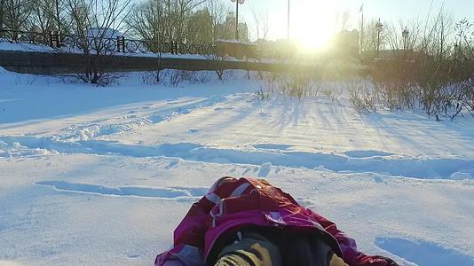 冬天公园里的孩子冬天日落小女孩在雪中坠落视频的预览图