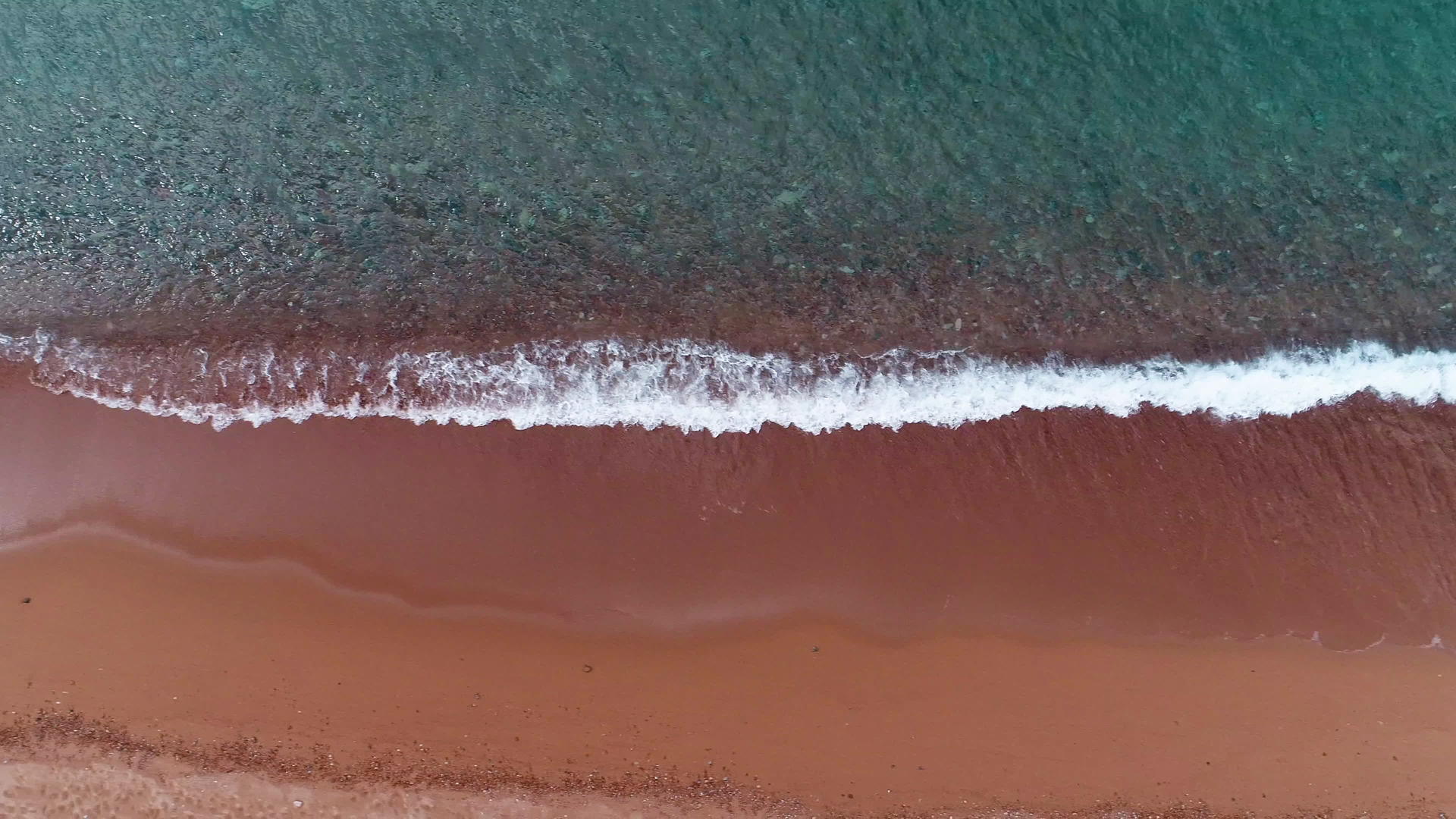 观察在红色海滩附近喷洒海浪和清洁水视频的预览图