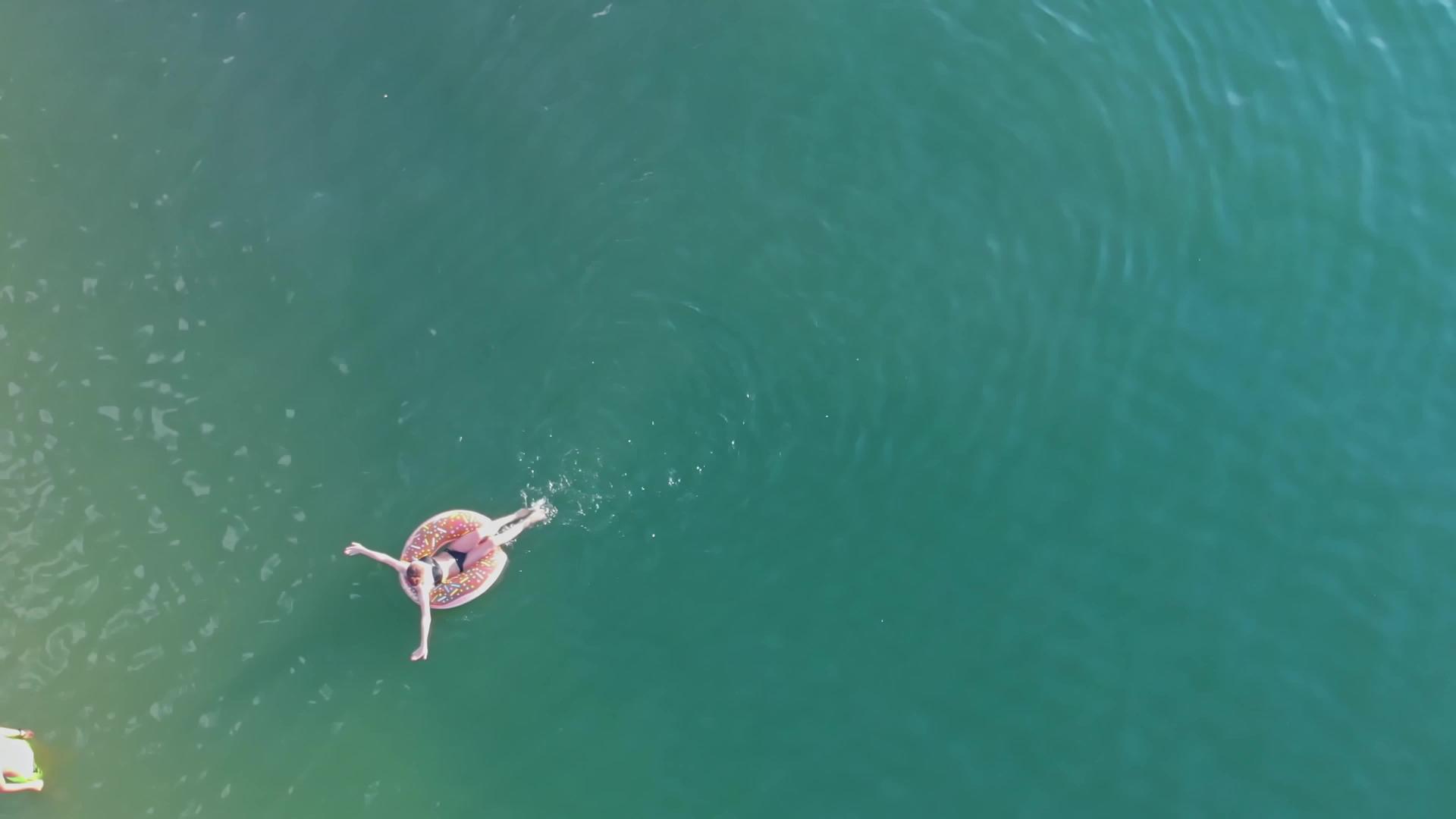 一个女孩漂浮在湖边海边的充气环上有一个男人在那里等着视频的预览图