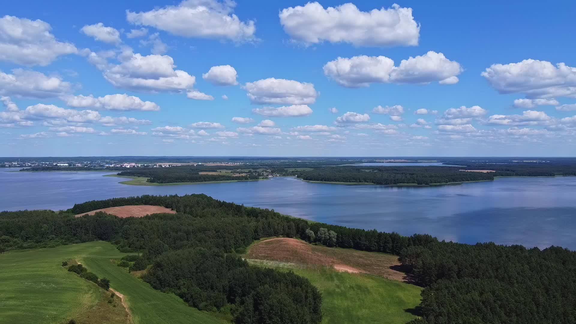 无人机平稳地俯瞰着湖面的蓝天和绿地视频的预览图