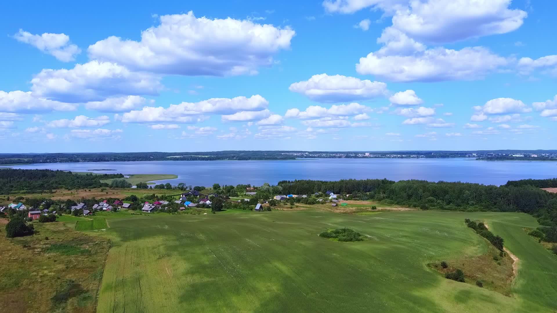 无人机漂浮在绿地上俯瞰蓝湖和蓝天视频的预览图