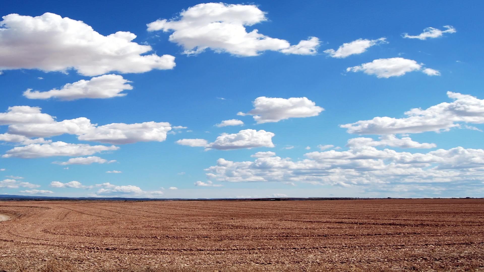 白云在天空中飞过棕色的田野视频的预览图