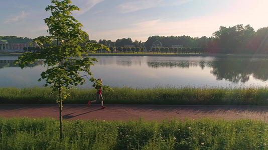 在美丽的公园里年轻健康的女性在阳光明媚的早晨和阳光明媚的公园里慢跑视频的预览图