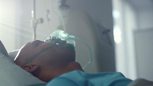带氧气面罩的康复患者躺在床上急诊室病房视频的预览图