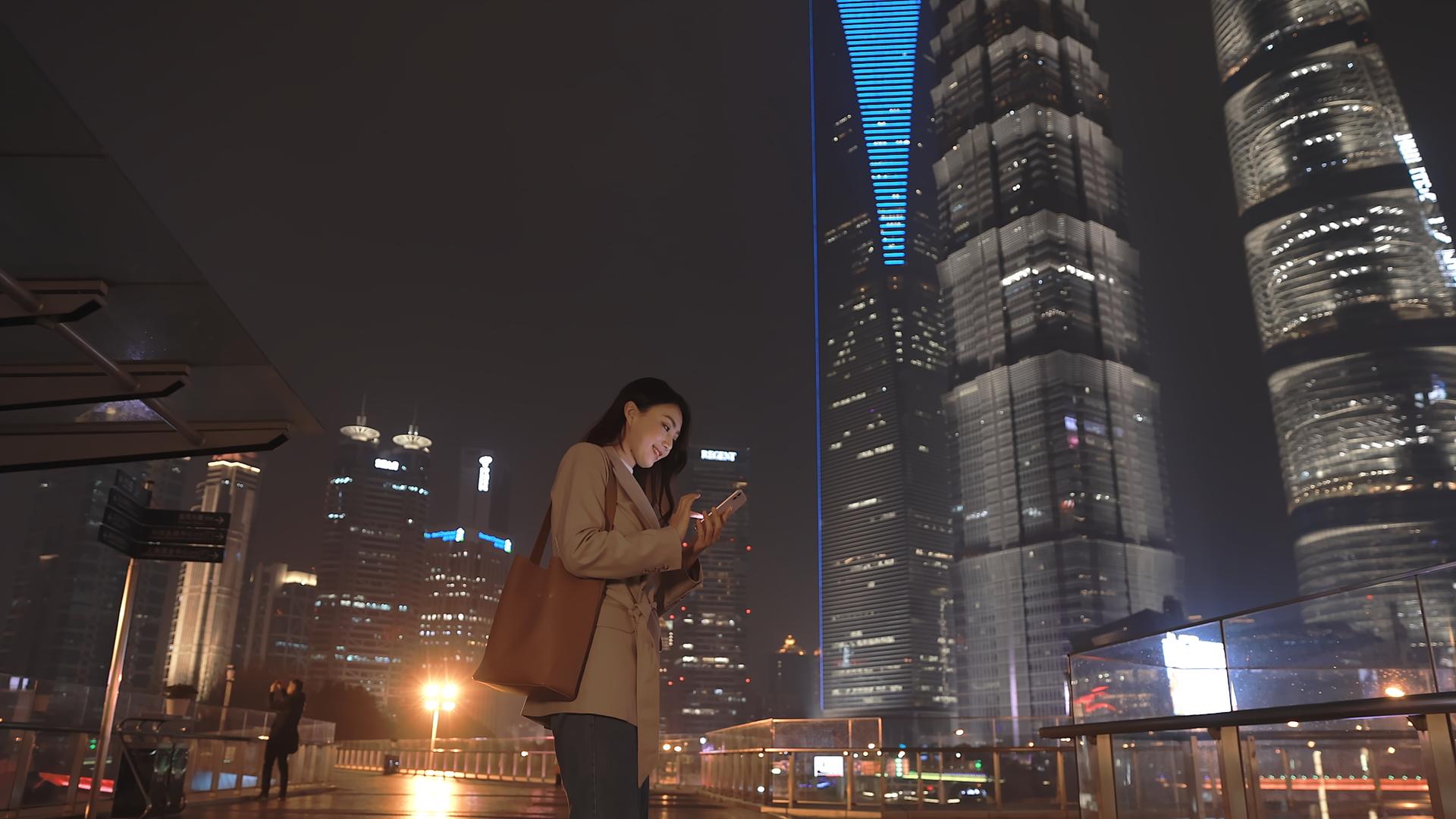4K冬季夜晚商务楼前女性看手机升格100p视频的预览图