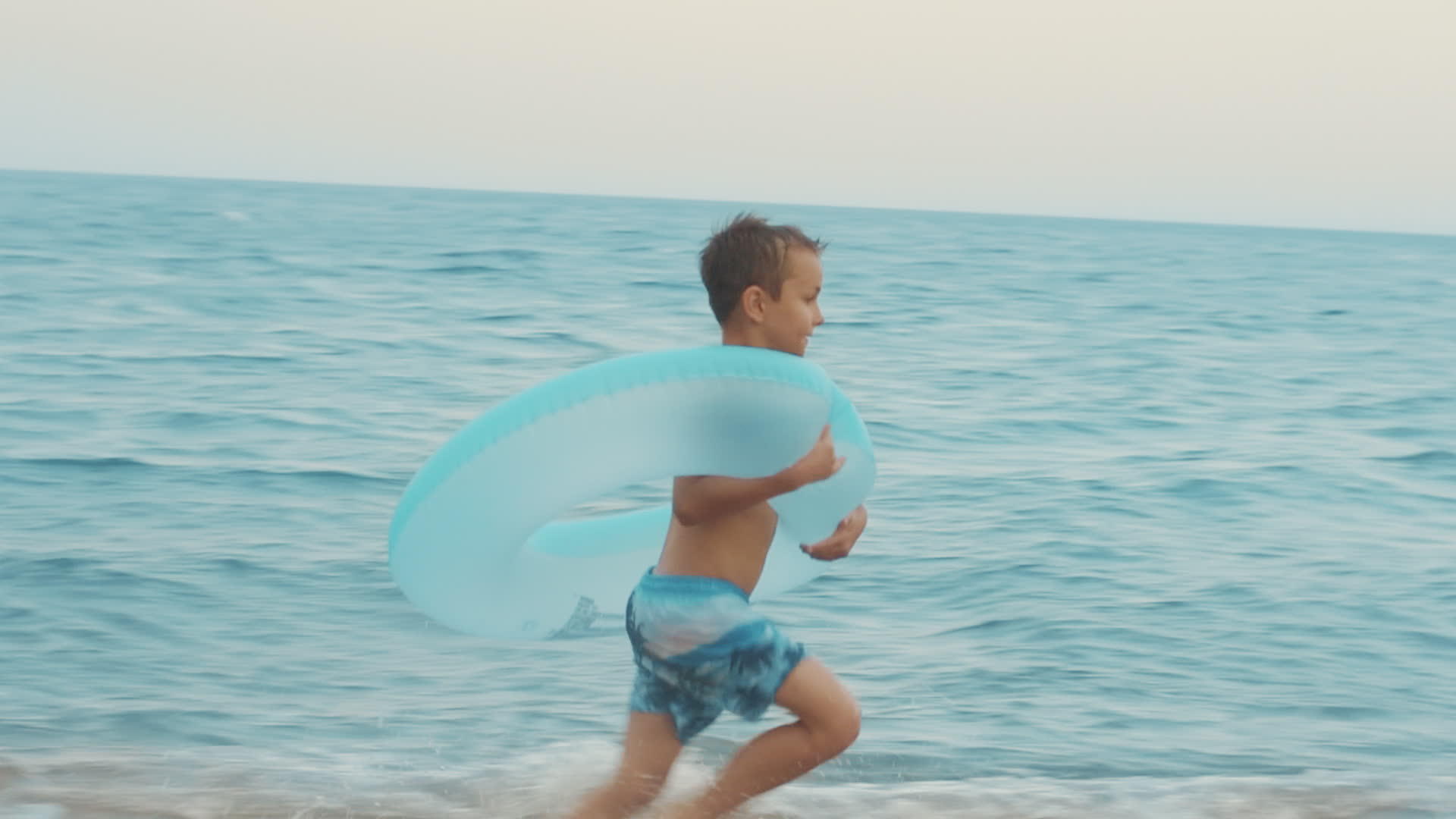 小男孩背着游泳圈跑向大海视频的预览图