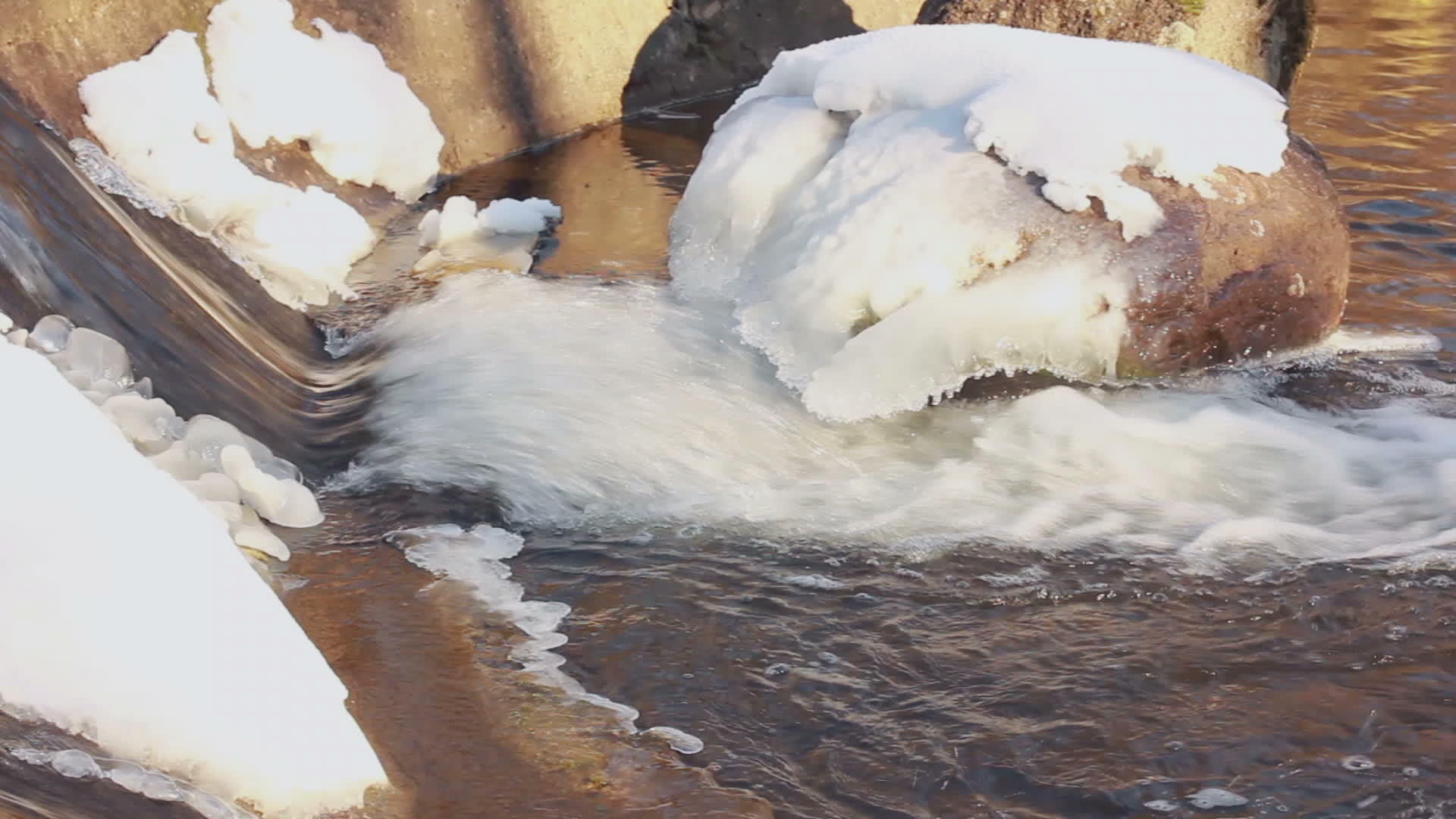 冬天的水在冬天的小瀑布石上流动着雪视频的预览图