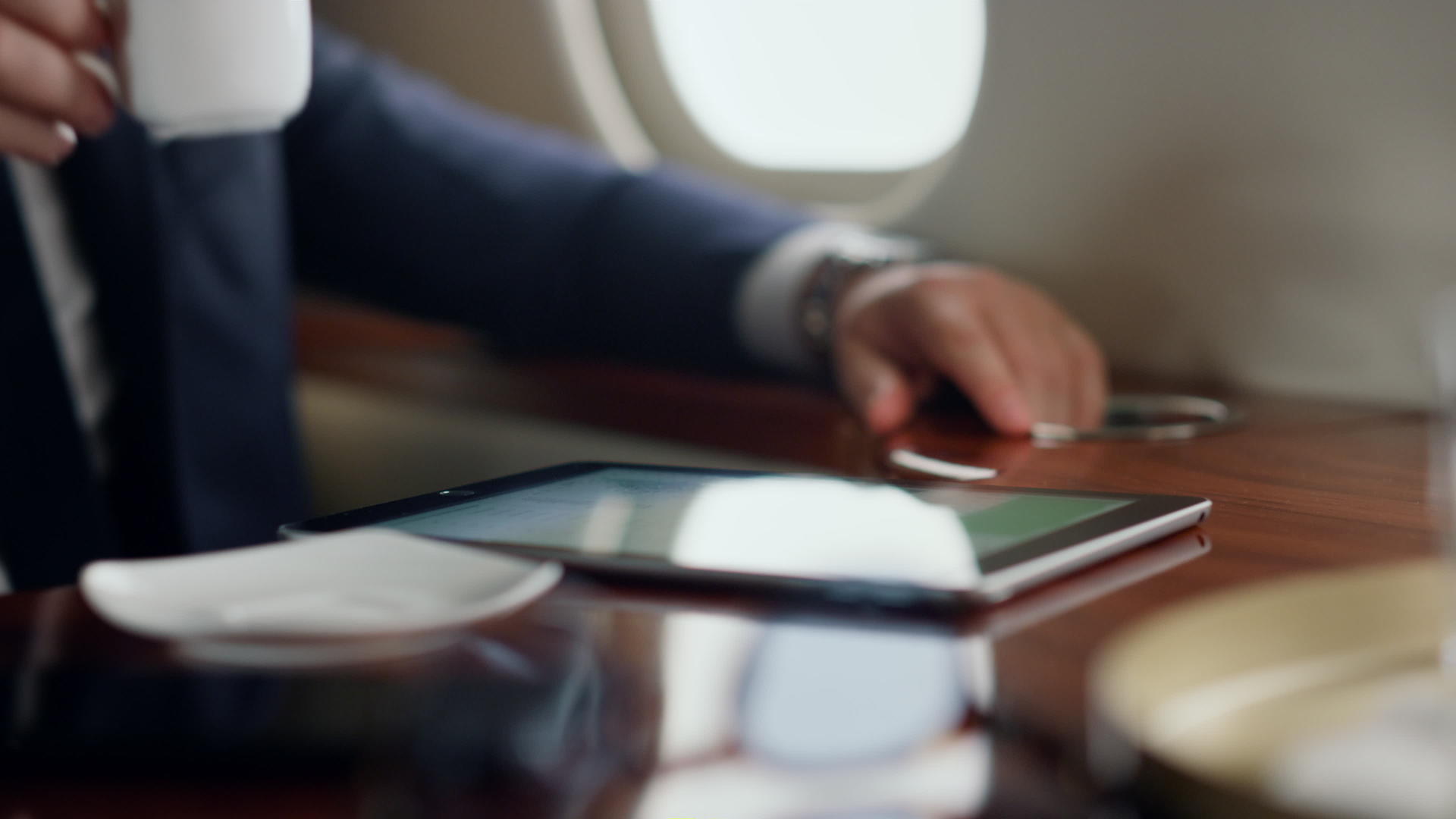 这名男子坐在飞机上喝咖啡桌上的数字电脑特写视频的预览图