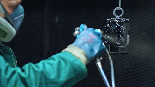 在工厂的机器零件上喷涂黑色油漆视频的预览图
