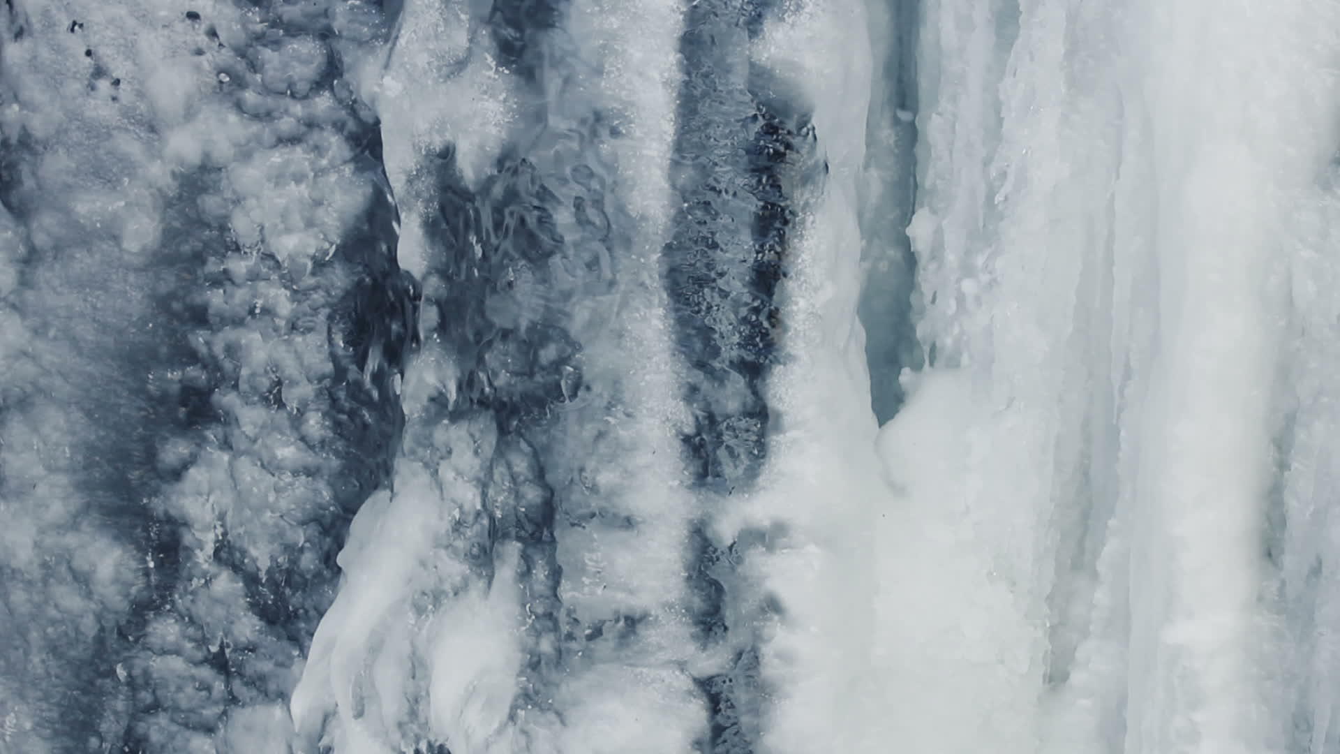 冰冷的瀑布水在冰下流动闭合视频的预览图