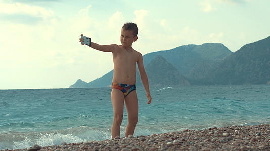 小男孩暑假在海边度假用手机自拍视频的预览图