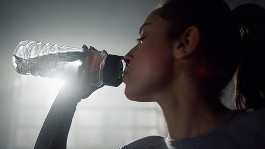 女孩从健身瓶里喝水站在体育俱乐部里视频的预览图
