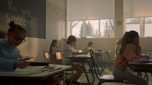 孩子们坐在教室的书桌前准备上课视频的预览图
