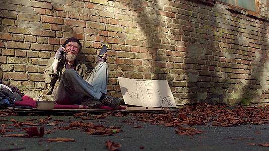 在阳光明媚的一天无家可归的老人用太阳能电池充电视频的预览图