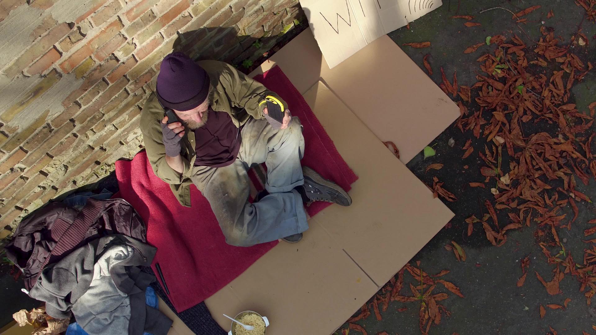 无家可归的人坐在阳光下拿着太阳电池视频的预览图