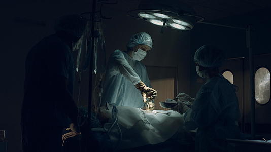 自信的外科医生在黑暗无菌诊所的急诊室接受手术视频的预览图