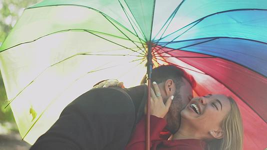 一对夫妇在公园里的彩虹伞下行走视频的预览图