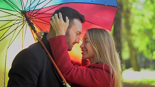 一对夫妇在公园里的彩虹伞下行走视频的预览图