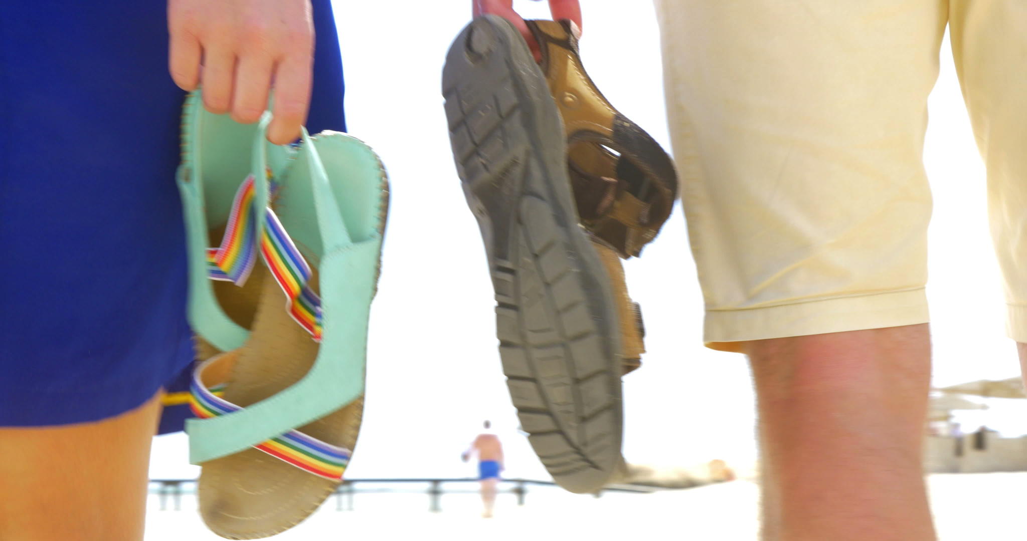 一对夫妇手里拿着凉鞋在海滩上走着视频的预览图