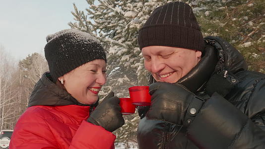 快乐的情侣喝热茶 冬天在雪林里散步视频的预览图