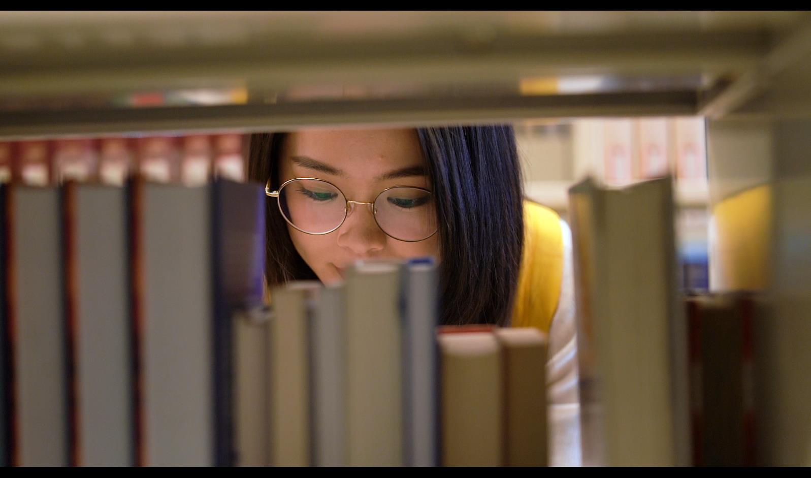 图书馆女书在书架上找书慢动作视频的预览图