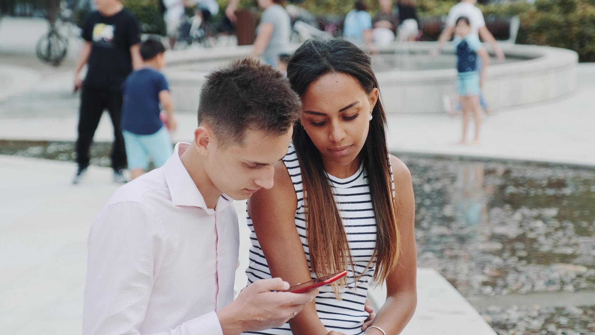 女混血女孩告诉她的男朋友不要整天看智能手机并要求她的男朋友停止视频的预览图