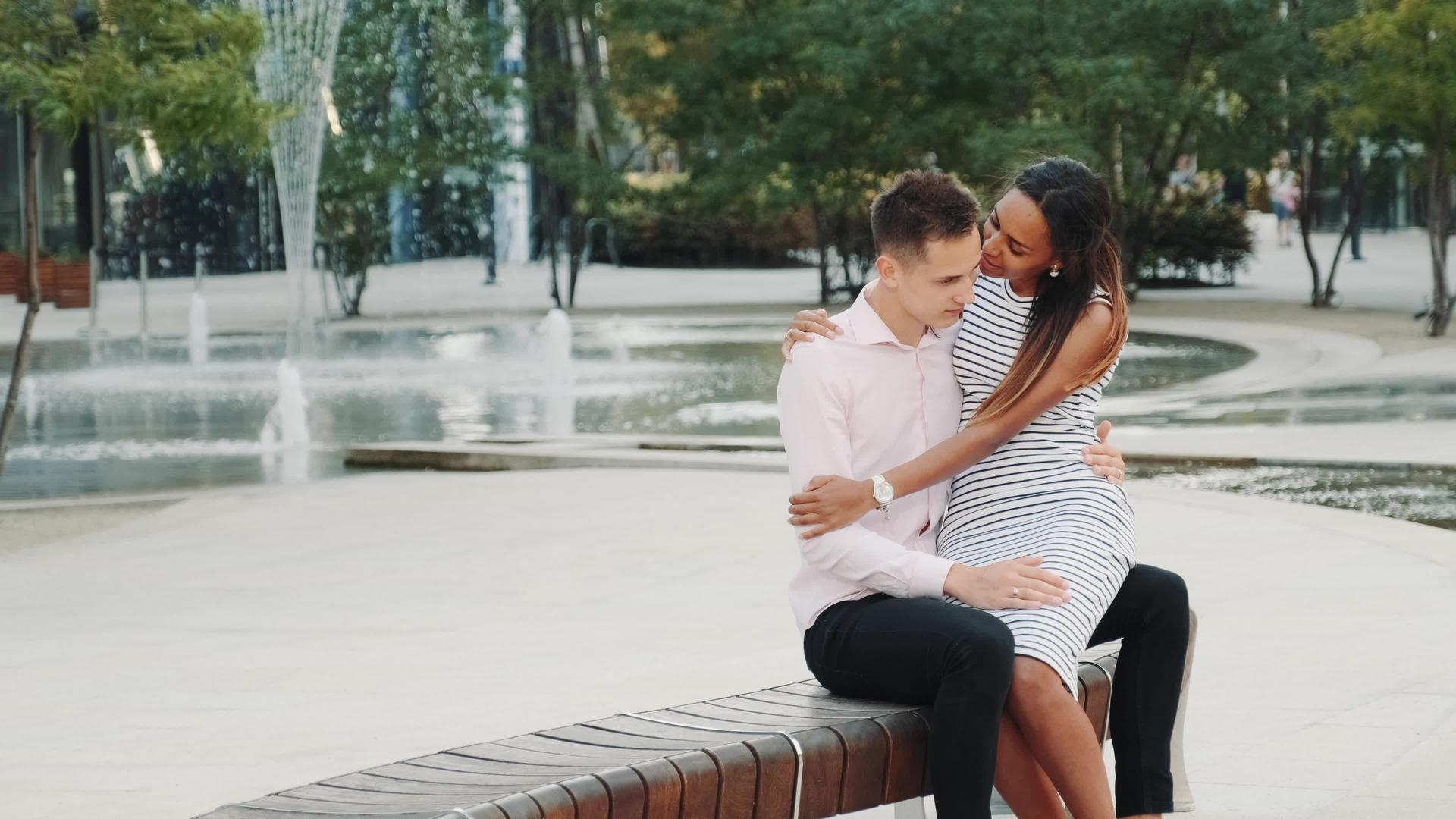 男人和女人坐在公园的长在公园的长椅上拥抱和交谈视频的预览图
