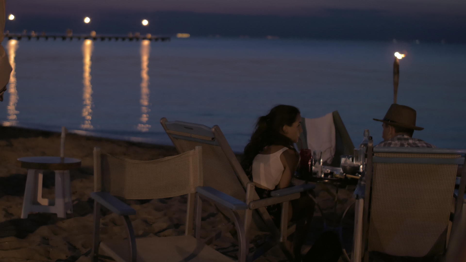看着年轻快乐的恋人在海滩上吃浪漫的晚餐视频的预览图
