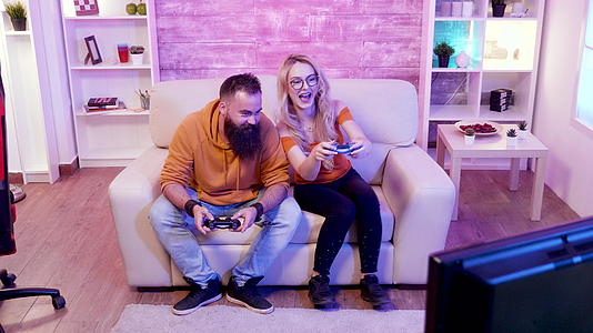 一对快乐的情侣坐在沙发上玩网络游戏视频的预览图