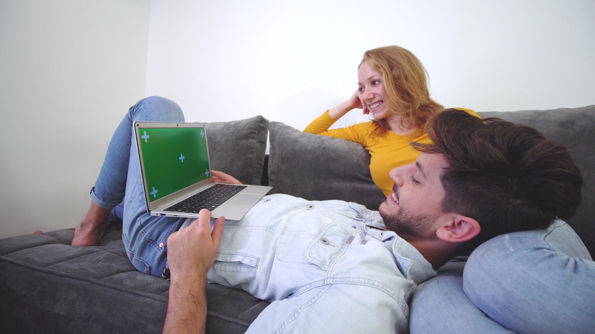 一对夫妇看着沙发上的笔记本电脑男孩躺在女孩的腿上视频的预览图