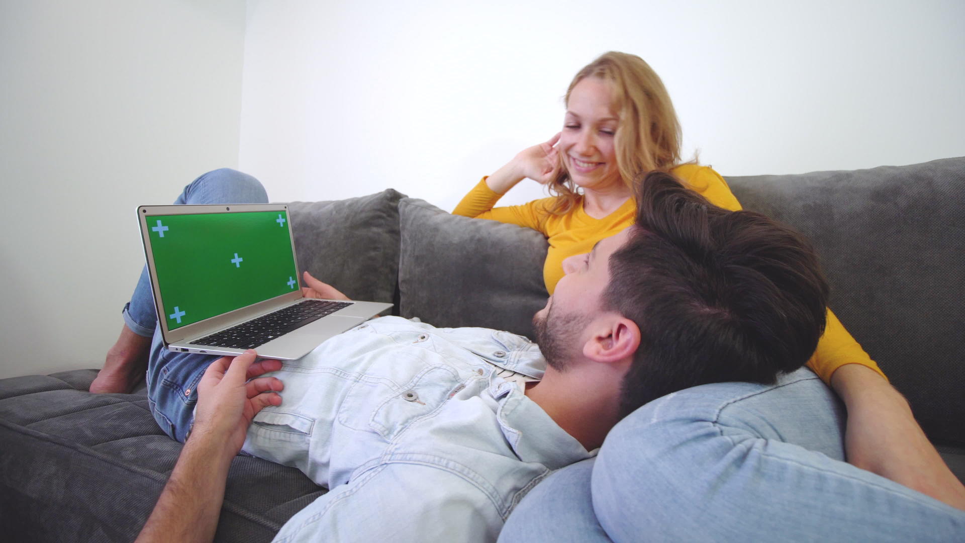 一对夫妇看着沙发上的笔记本电脑男孩躺在女孩的腿上视频的预览图