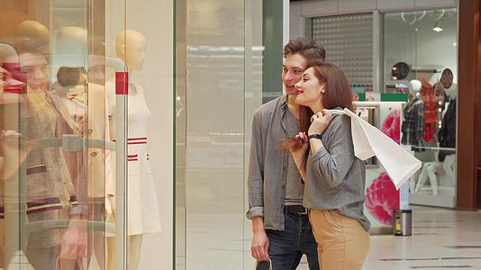 一对快乐的年轻夫妇一起购物检查商店展示的衣服和笑声视频的预览图