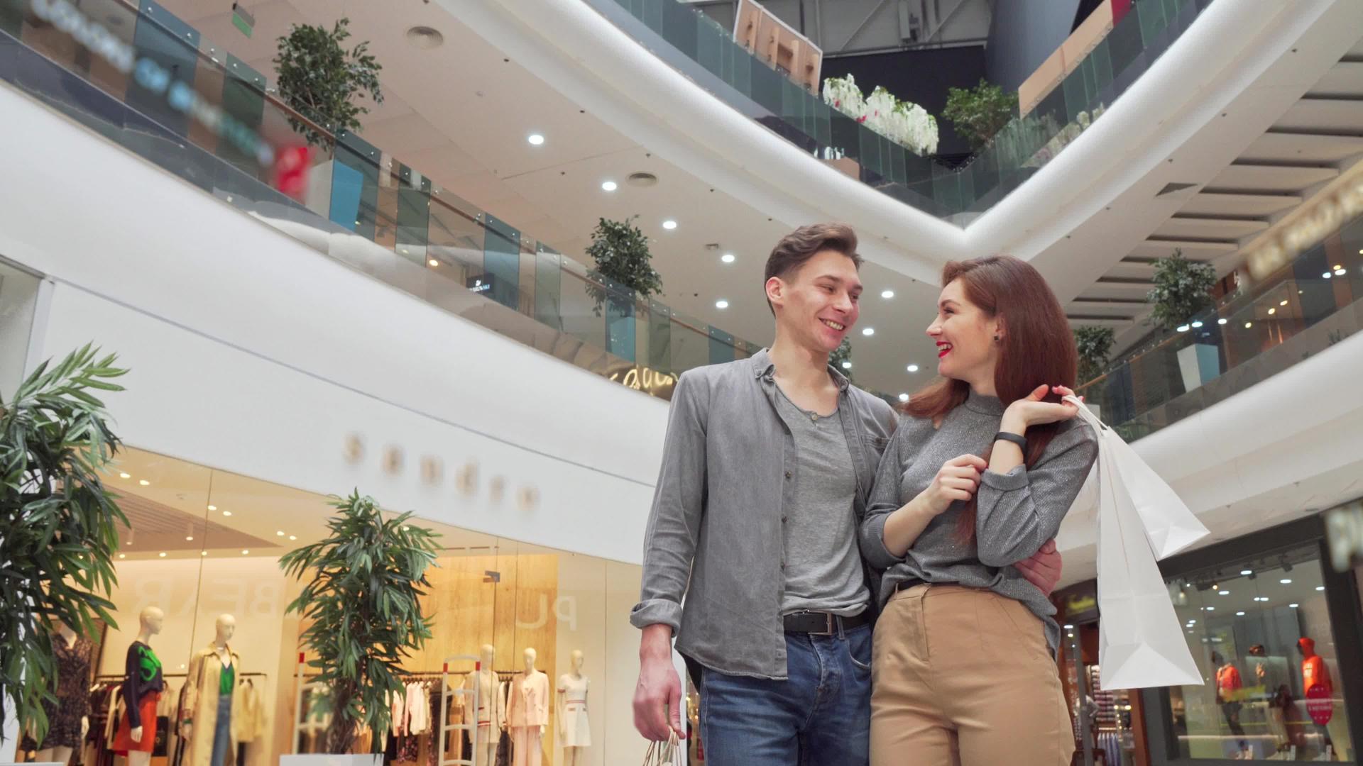 在购物中心周围低角度拍摄一对年轻夫妇的低角度镜头视频的预览图