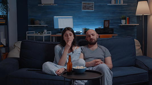 一对夫妇坐在沙发上哭泣在电视上看戏剧和电影视频的预览图